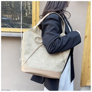 Detail of suede textured tote bag with decorative bow and reinforced PU leather bottom