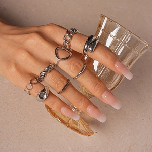 Silver geometric irregular rings set shown on hand holding a glass, minimalist style