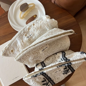 Detailed close-up of three French lace embroidery makeup bags with gold zippers