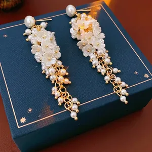 French vintage resin flower tassel earrings with pearls and gold beads on a blue velvet box