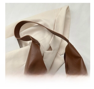 Detailed texture of dark brown lychee grain leather on a stylish minimalist hobo handbag