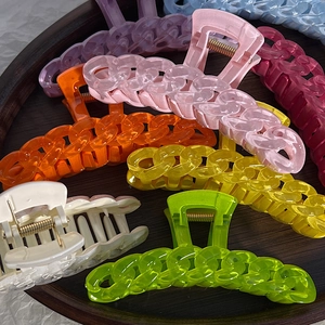 Candy colored chain hair claws in pink, blue and pearl white displayed on wood tray