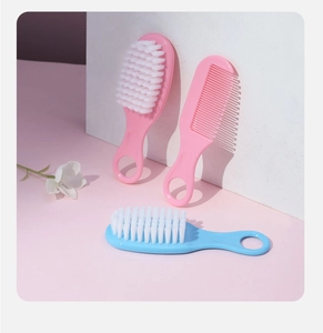Close-up of three-piece baby brush and comb set in pink and blue with soft bristles