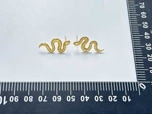Vue détaillée des boucles d'oreilles serpent dorées 18K avec texture d'écailles en relief