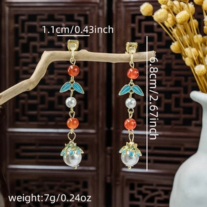 Detail of beaded tassel earrings with pearl drops hanging on a rustic wooden branch