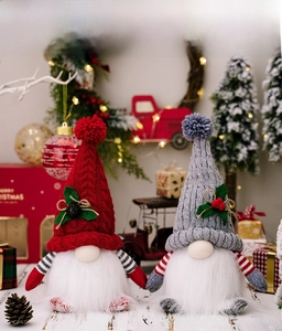 Close-up of red and grey knitted Christmas gnomes with glowing hats and white beards