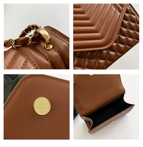 Macro view of brown quilted leather bag with V-shaped stitching and gold chain detail