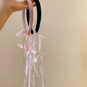 Close-up of pink and black satin headbands with crystal tassels and long bow ribbons