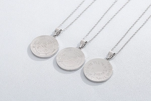 Detailed view of silver coin pendants with engraved runes and inspirational quotes on white