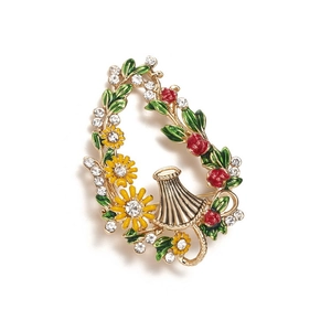 Detail of floral enamel brooch with daisy, sunflower and red berries in gold basket