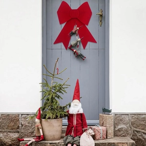 Detail of red PVC flocked Christmas bow with hanging ornaments on a front door