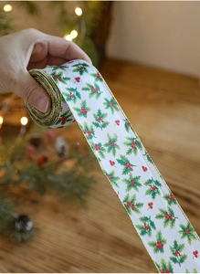 Close-up of white Christmas ribbon with holly leaf print and gold wire edges