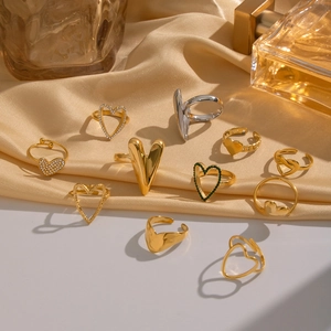 Detailed collection of gold and silver heart rings on a warm satin fabric background