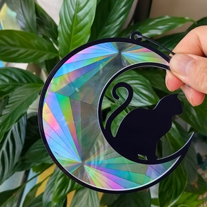 Detailed view of black cat sitting on a rainbow prism crescent moon suncatcher