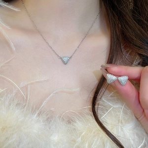 Gros plan d'un ensemble collier et boucles d'oreilles triangle argenté avec zircons