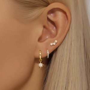 Macro shot of gold star charm earring and diamond hoop set featuring crystal zircon