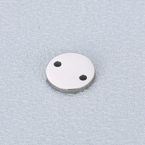 Macro detail of polished stainless steel round charm with two holes for DIY jewelry