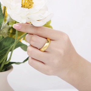 Vue rapprochée d'une bague en acier doré poli portée par un mannequin avec des fleurs
