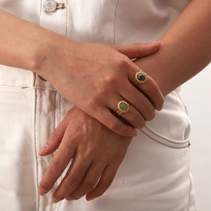Detail of twisted gold titanium steel rings with oval African pine stones on white denim