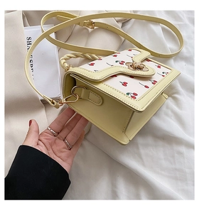 Close-up of light yellow cherry print handbag featuring metal turn-lock and handle