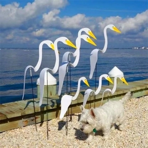 Set of eight white swirl bird garden stakes displayed on a sunny beach boardwalk
