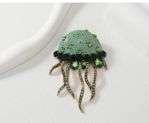 Detailed view of jellyfish brooch with green crystals and flowing rhinestone tassels