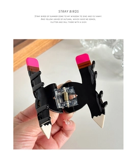 Close-up of creative pencil-shaped hair claw clip with glossy finish and spring detail