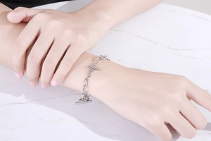Macro detail of silver heartbeat lifeline bracelet with toggle clasp on marble background