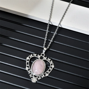Gros plan d'un pendentif coeur en argent avec pierre rose et détails filigranes