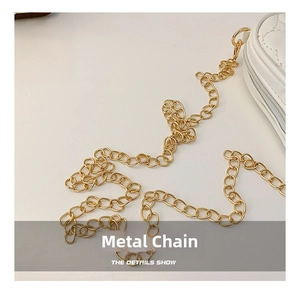 Detailed close-up of the bright golden hardware chain on a white quilted crossbody bag