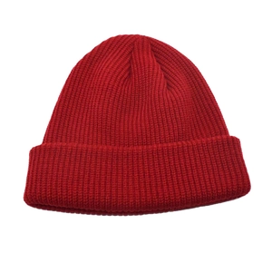 Close-up of red knit beanie showing thick ribbed texture and wide cuffed brim for winter