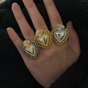 Anelli vintage Sacro Cuore in finitura oro e argento sulla mano con maglione nero
