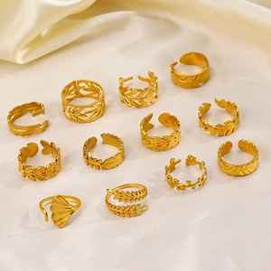 Set of 18K gold plated stainless steel leaf rings on beige silk fabric background