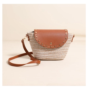 Close-up of woven straw texture with brown leather flap and gold rivet detail