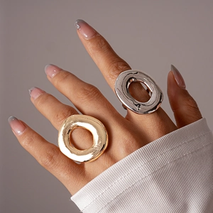 Close-up of chunky gold and silver hollow oval rings on finger with metallic finish