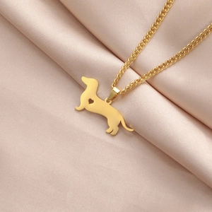 Detail of golden dachshund dog pendant with heart cutout on champagne silk fabric