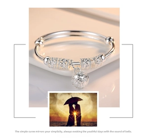 Close-up of silver bell charm and hollow beads on adjustable push-pull bangle