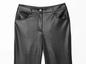 Detailed close-up of the waistband, metal button, and pocket of black faux leather pants