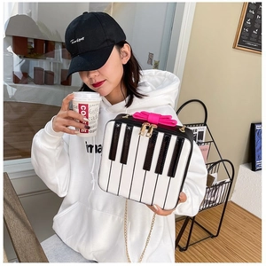 Detail of creative piano keyboard bag with pink bow and gold chain strap in a cafe setting
