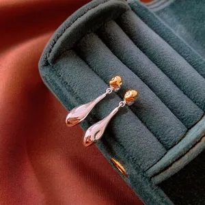 Two-tone water drop earrings in gold and silver finish placed in a velvet jewelry box