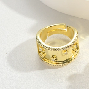 Detailed view of wide gold ring with zircon stones and star engravings on white background