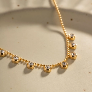 Detailed macro view of a gold-plated beaded necklace with sparkling bezel-set crystals