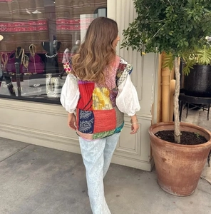 Rear view of bohemian patchwork sleeveless vest paired with white puff sleeve top