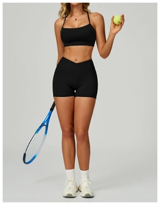 Detail of high-waisted black yoga shorts with V-cross waistband and tennis racket prop