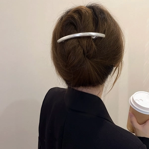 Close-up of a minimalist silver metallic hair clip on a woman's updo with matte finish