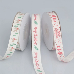 Close-up of Merry Christmas patterns on three rolls of cream fabric holiday ribbons