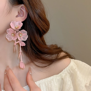 Detail of pink mesh flower tassel earrings with zircons shown on a model's ear