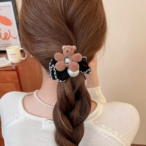 Detailed shot of a brown flocking bear hair tie with pearl and crystal on a ponytail