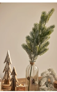 Detailed close-up of flocked artificial pine branch in a glass vase for Christmas decor