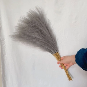 Hand holding 55cm fluffy grey faux pampas grass bouquet for boho home decor